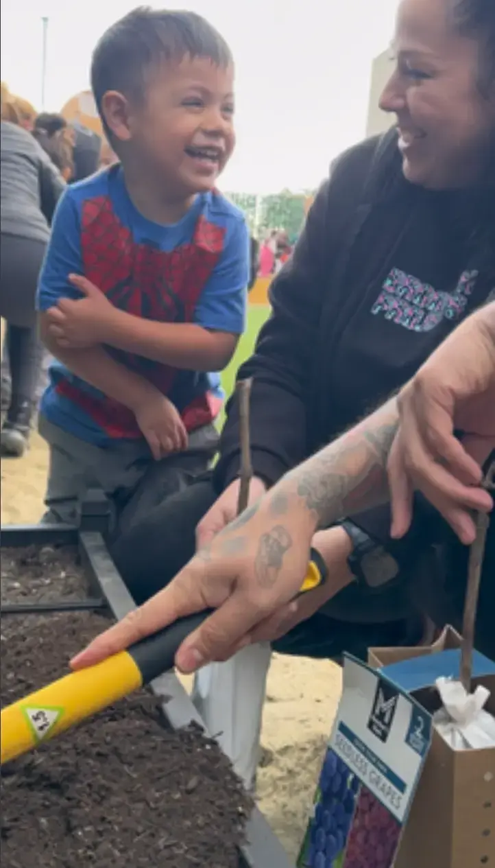A family participating in a community garden planting day event at GMCC early learning center