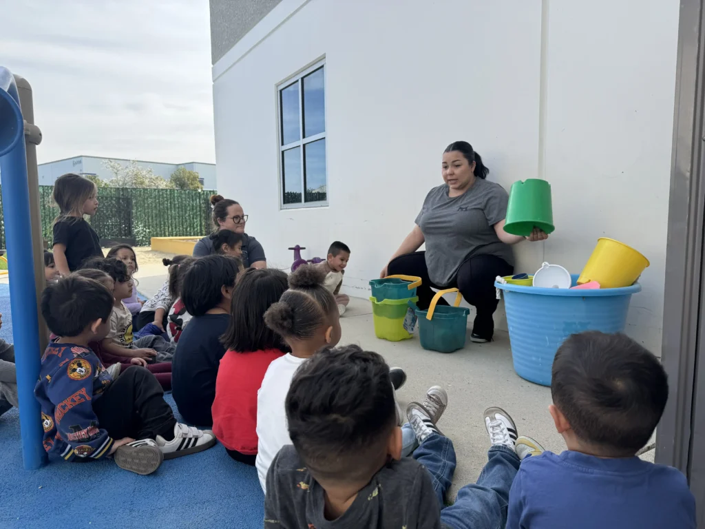 A teacher engaging children in an outdoor lesson with colorful learning materials at GMCC