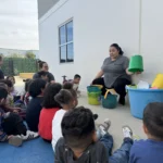 A teacher engaging children in an outdoor lesson with colorful learning materials at GMCC