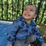 A happy toddler smiling during outdoor playtime at the GMCC early learning center