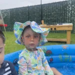 A toddler enjoying water play in a kiddie pool during summer activities at GMCC childcare